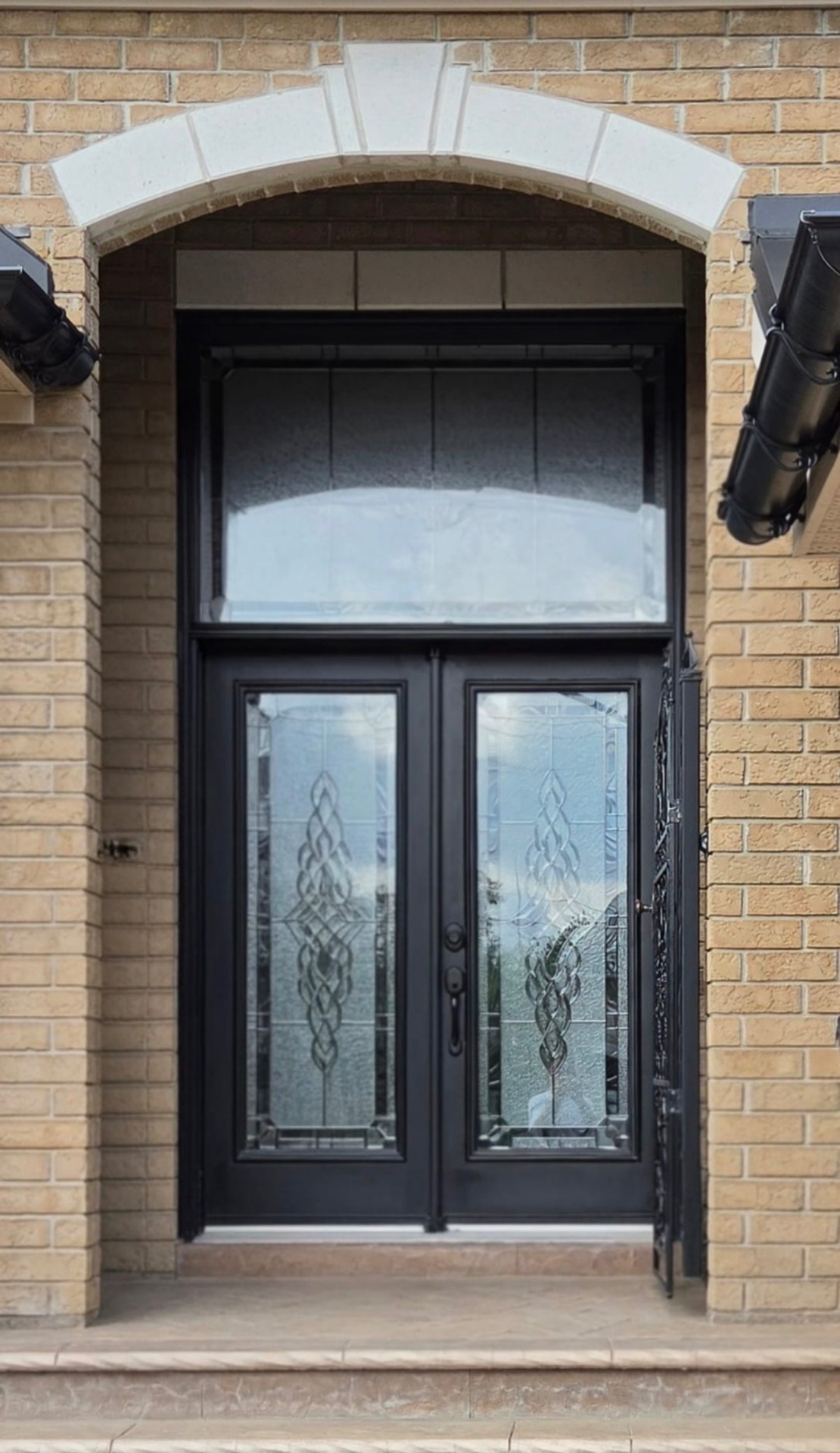 Black double entry doors with decorative glass and transom