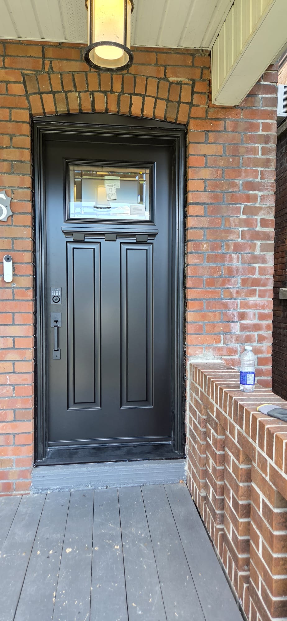 Black two-panel entry door with dentil shelf and transom lite