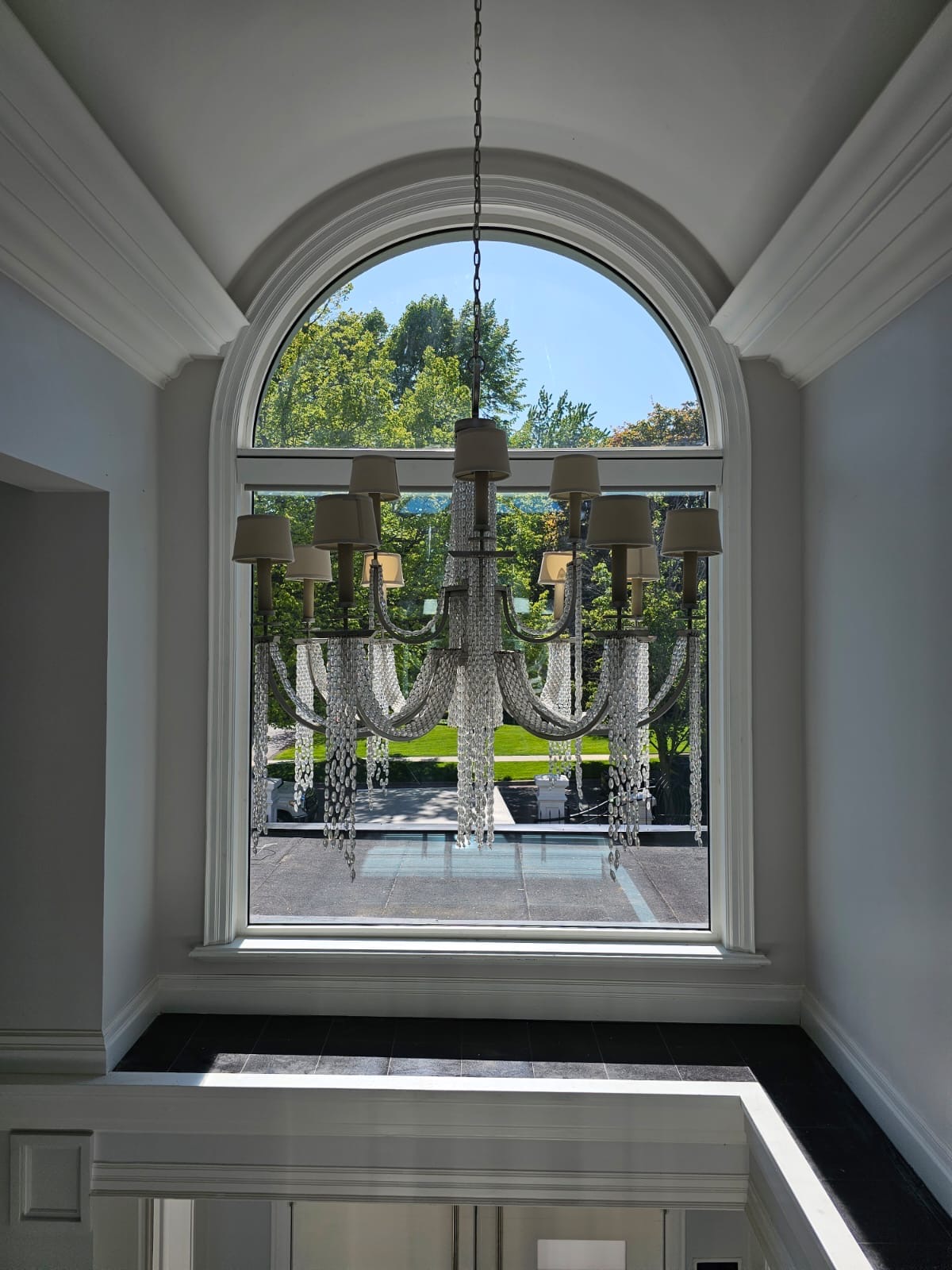 Interior view through the arched foyer window looking out to the front drive
