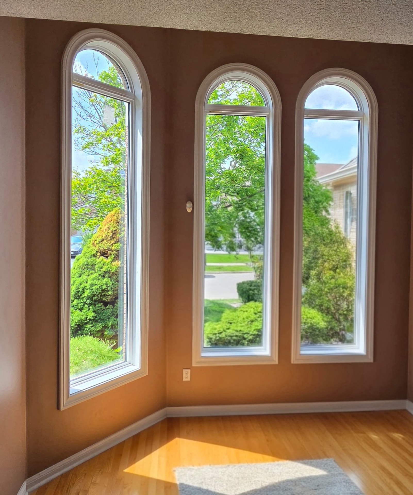 Interior view of three tall arched windows with white interior frames