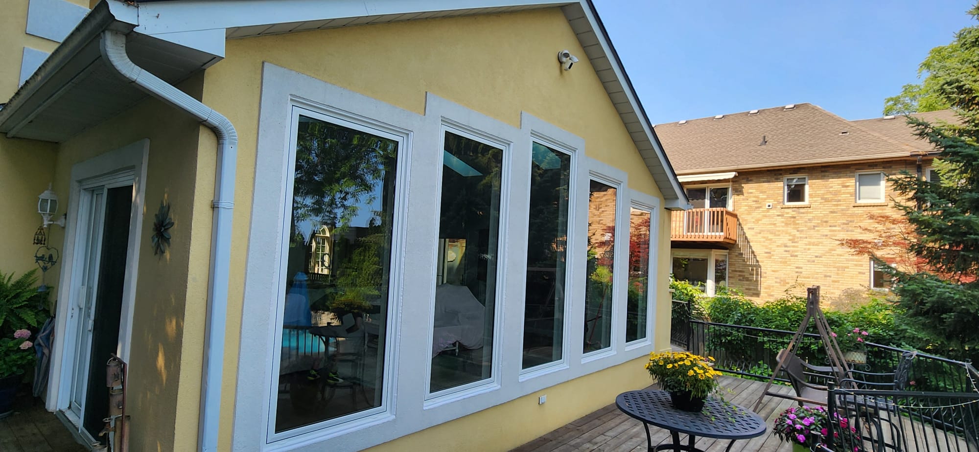 Five-panel picture window wall on the sunroom exterior with slim white frames