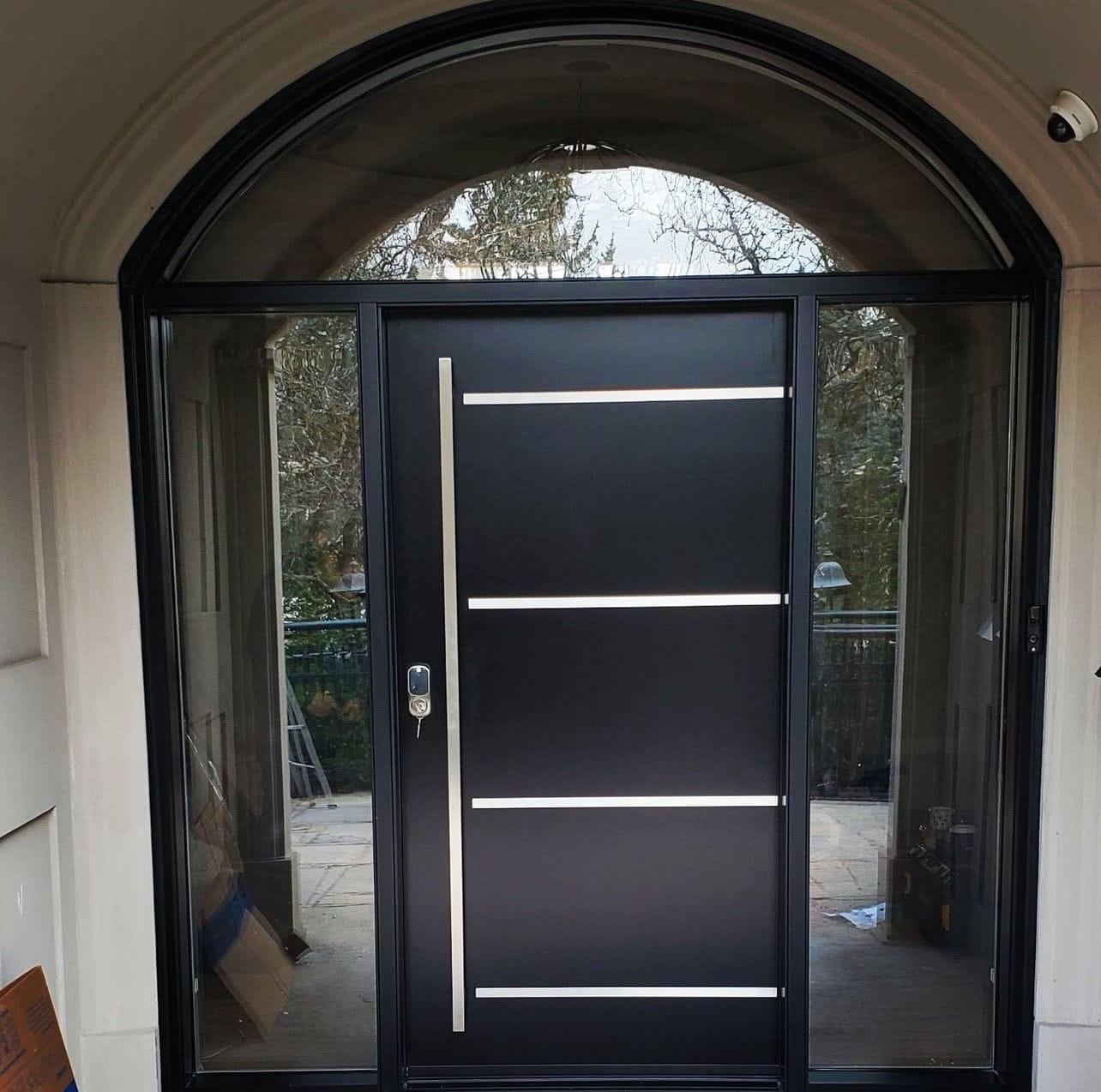 Modern black pivot entry door with arched transom and full sidelites