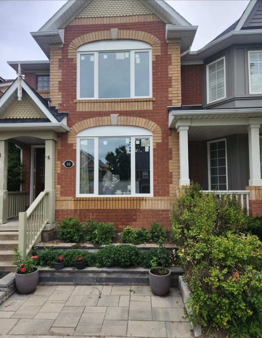 Custom white box-bay windows under brick arch surrounds