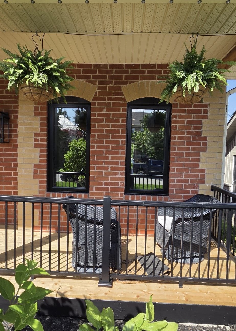 Covered front porch with two new slim black-framed casement windows