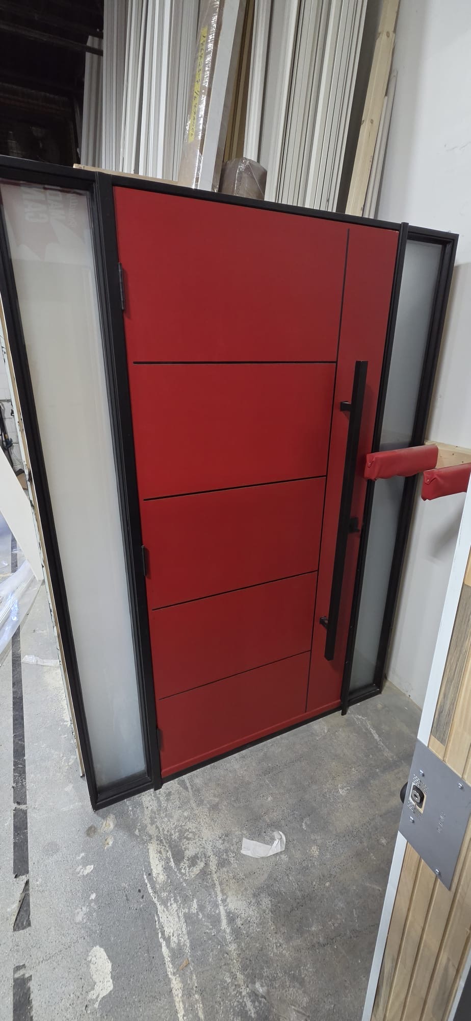 Bold red modern pivot entry door with black frame and frosted sidelites
