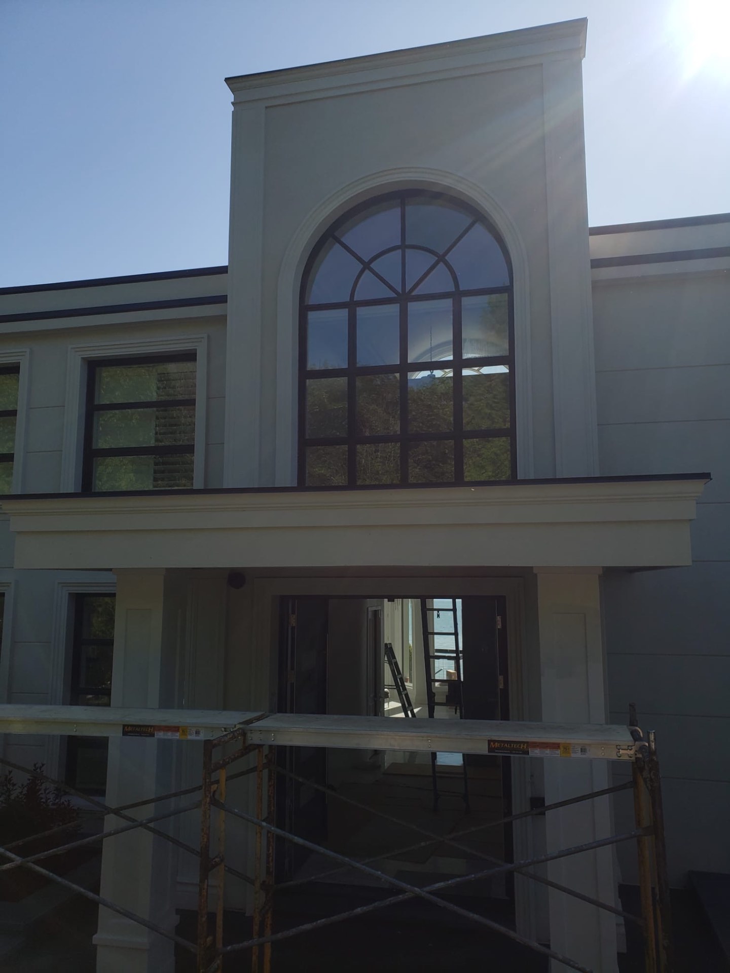 Two-storey arched picture window installed above the front entry with dark contrast frames