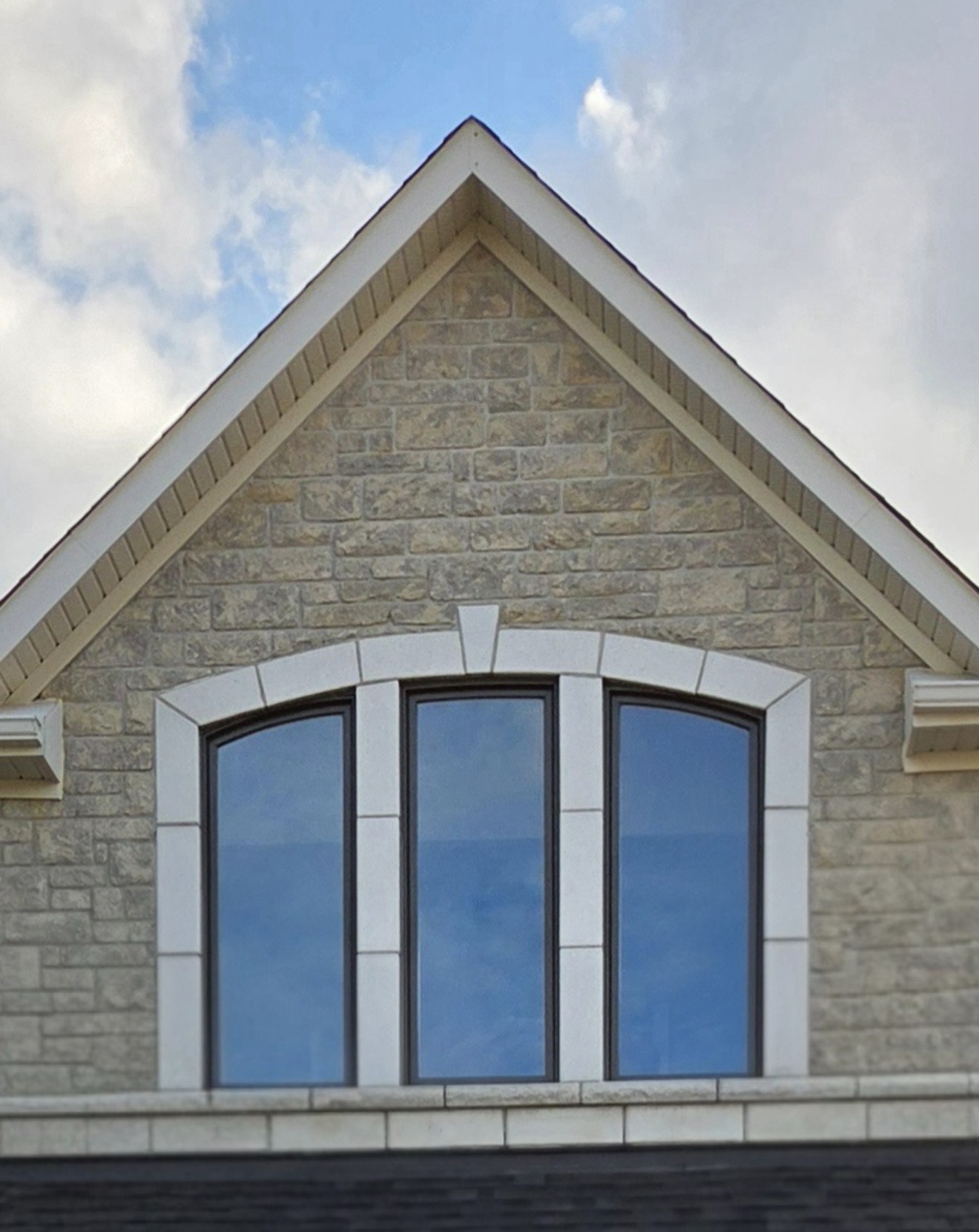 Arched black-frame gable windows on stone facade