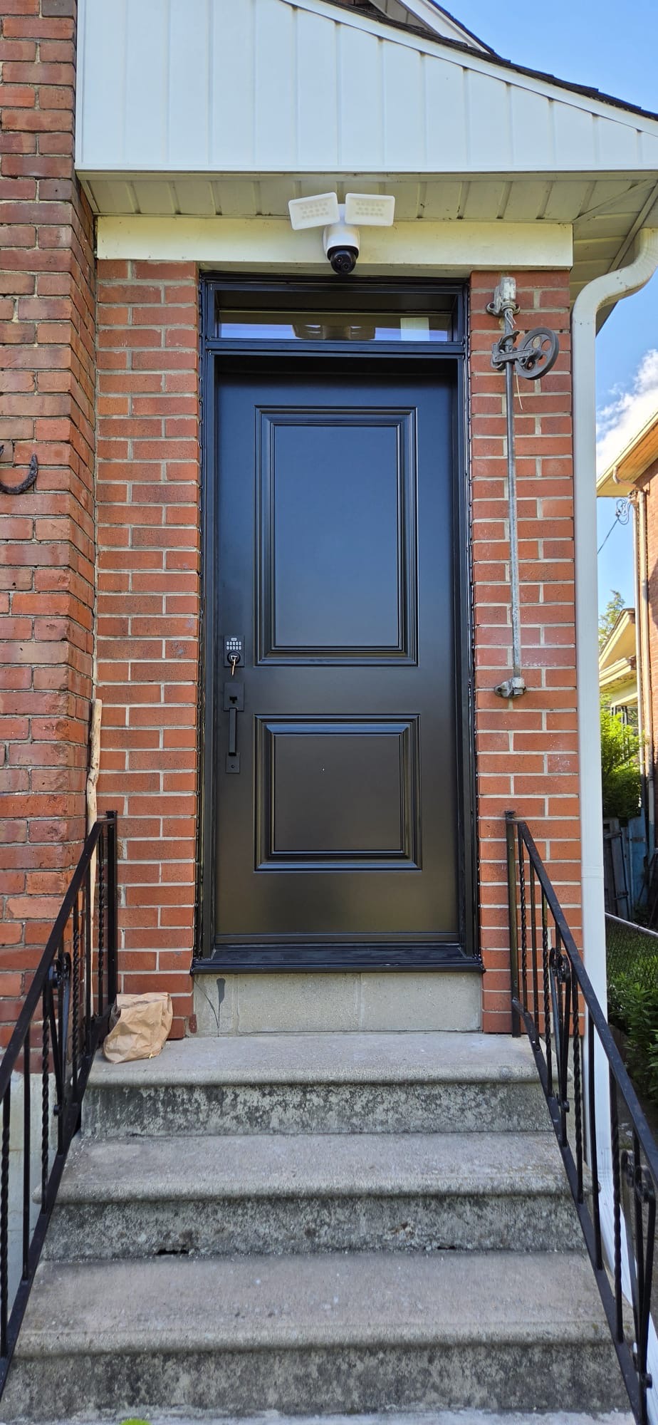Black two-panel entry with transom on red brick heritage home