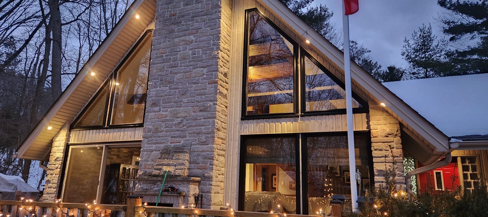 Twin A-frame shaped window walls glowing at dusk
