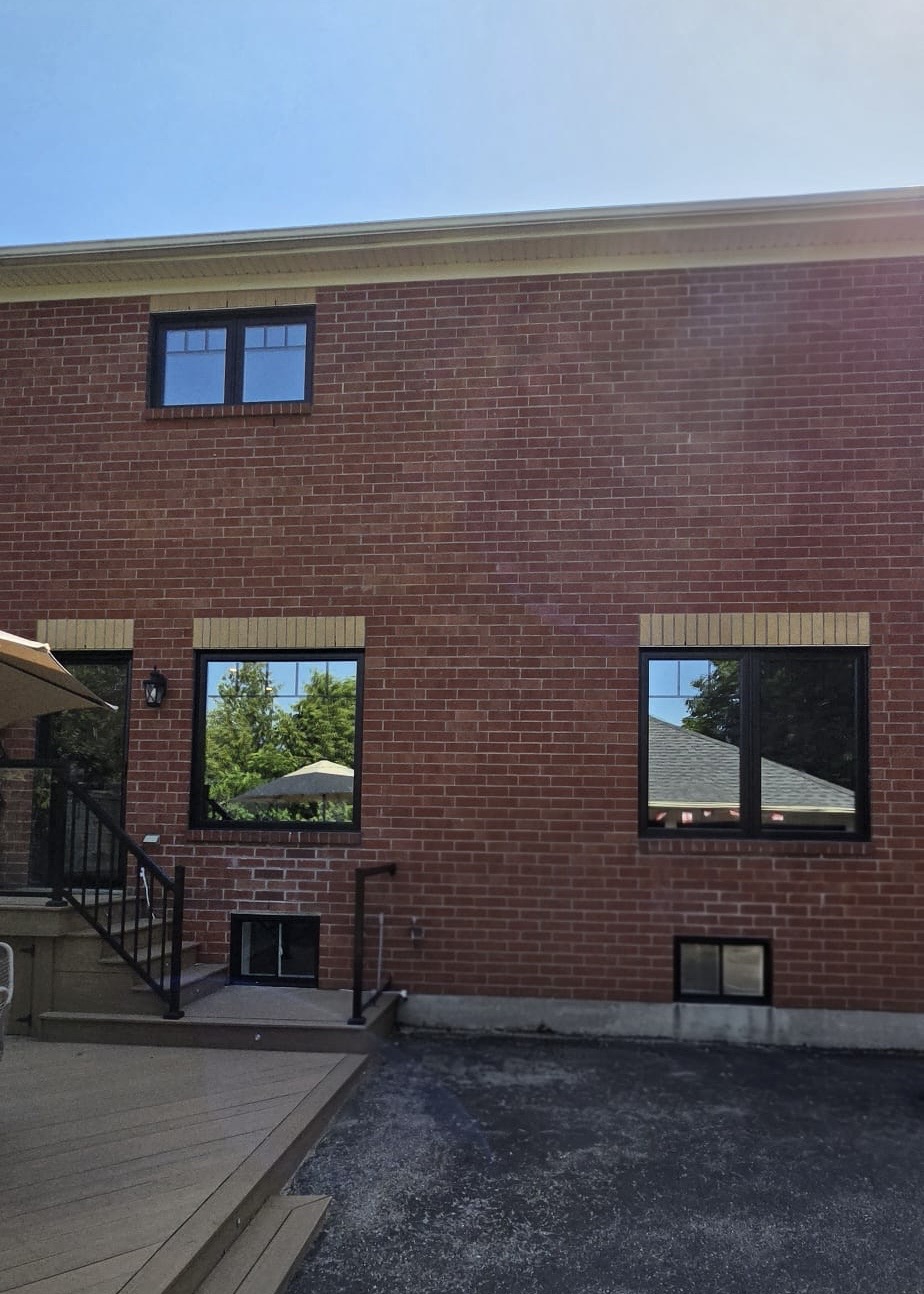 Rear brick wall with new black picture windows and basement sliders