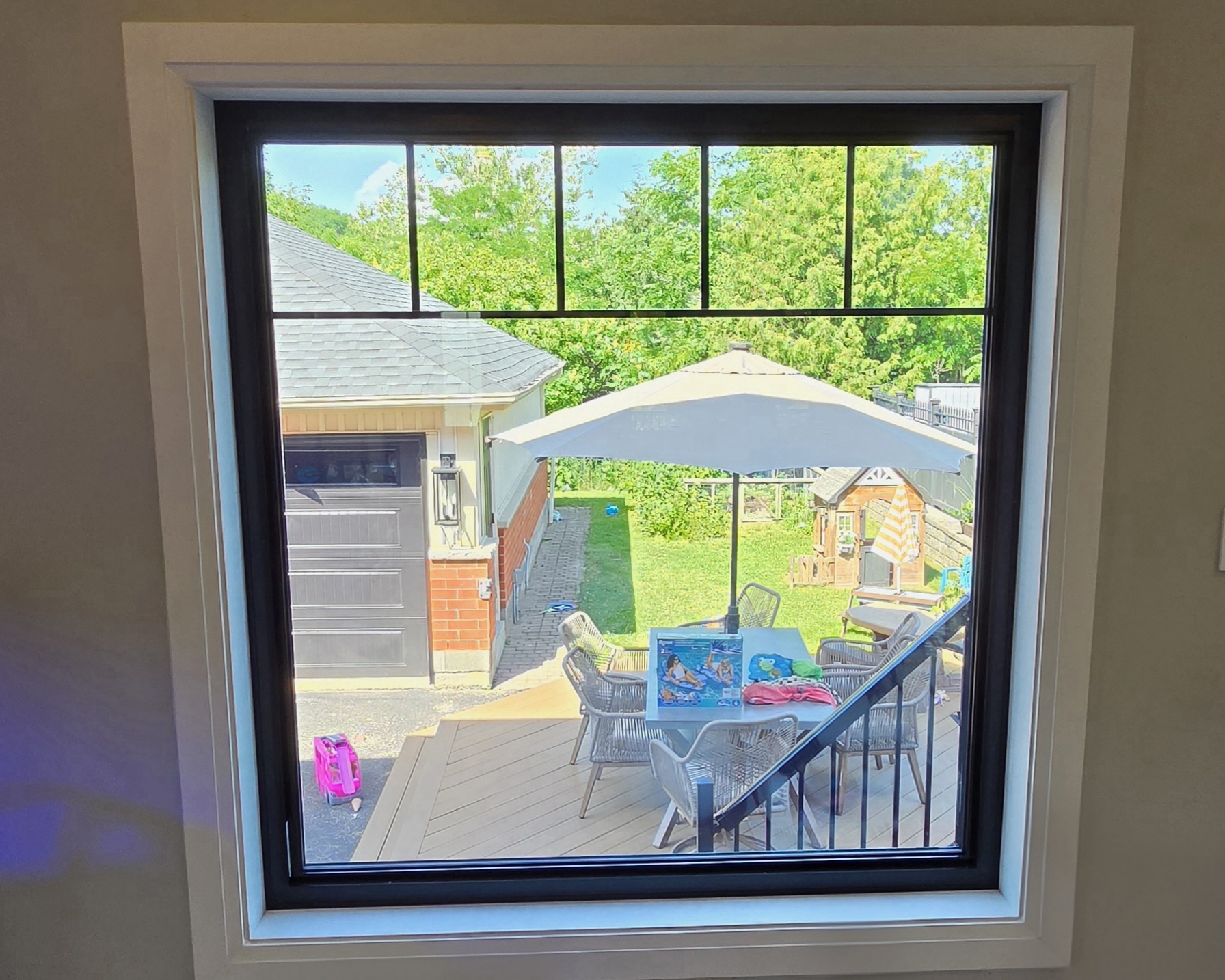 Interior view of a new black-framed picture window with transom overlooking the rear deck
