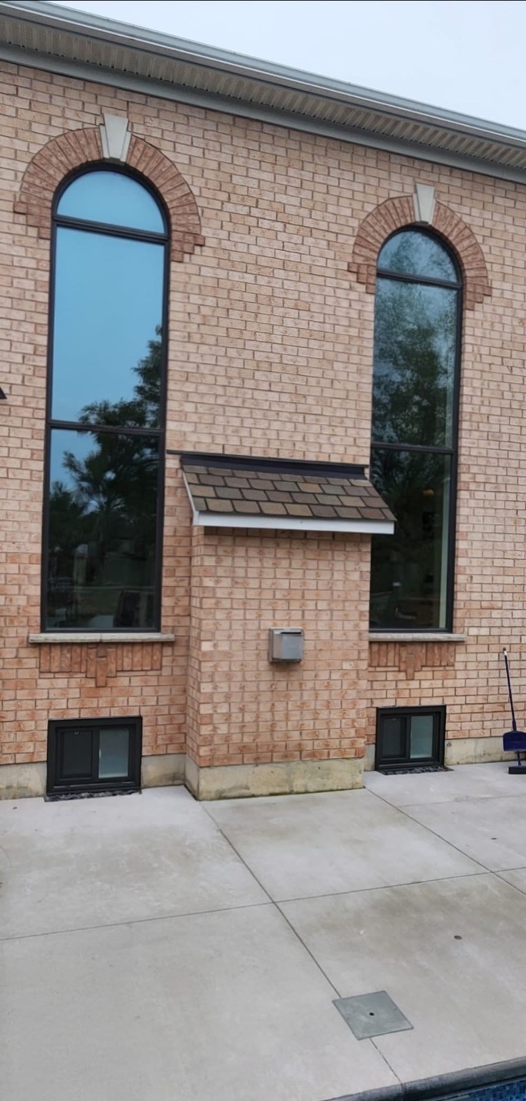 Tall half-round arched windows in black on a brick side elevation