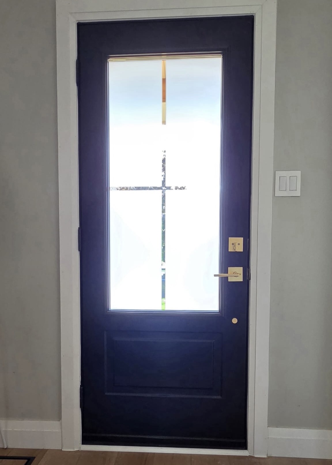 Interior view of the new entry door with frosted glass and brass lever hardware