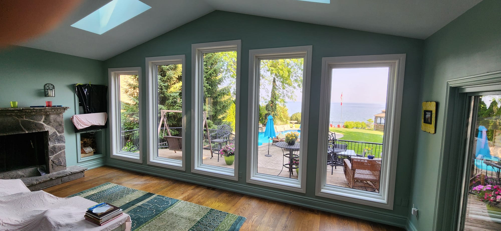 Interior view of the sunroom showing four floor-to-ceiling picture windows facing the lake