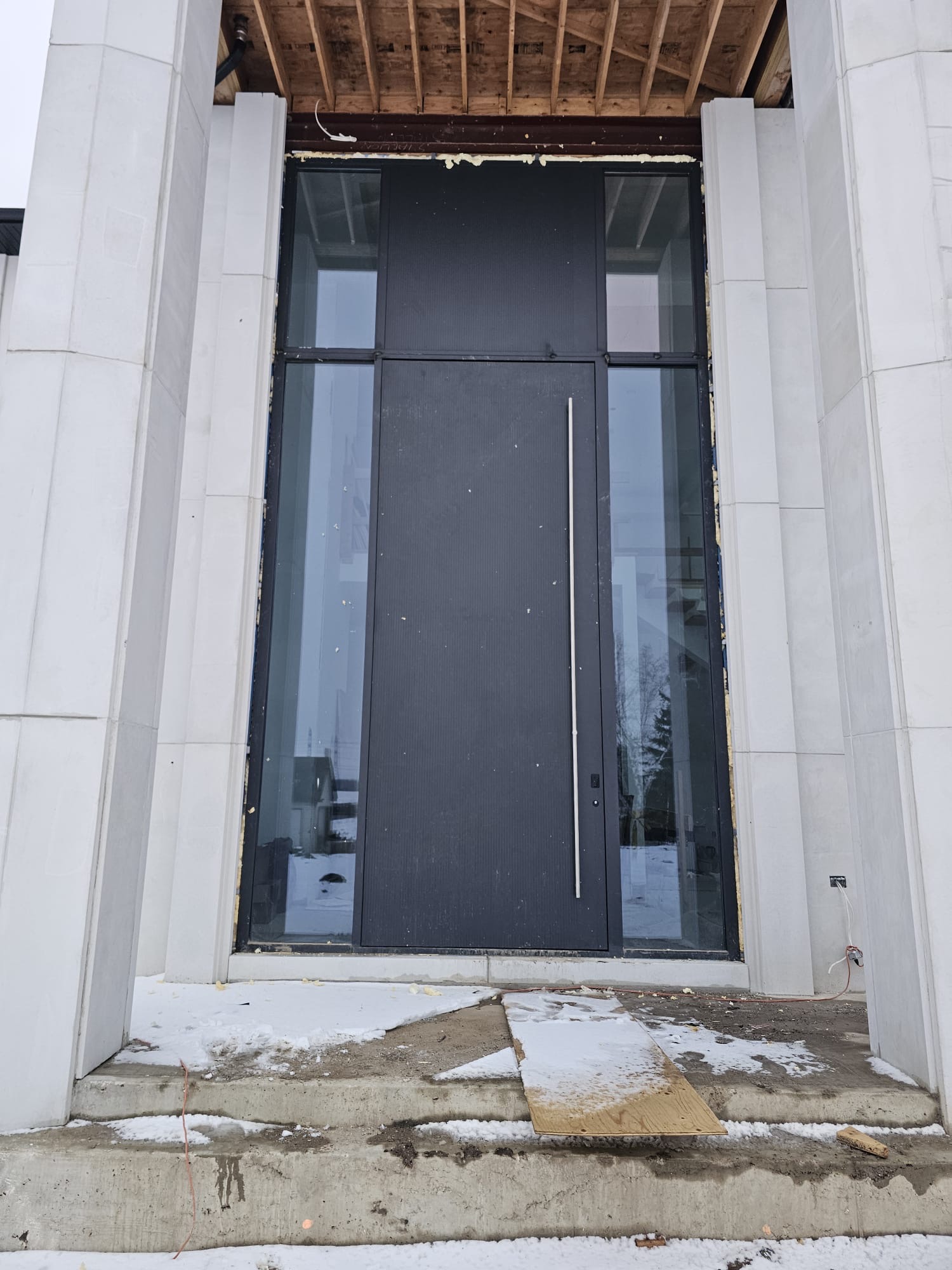 Modern black entry with tall transom and full-height sidelites
