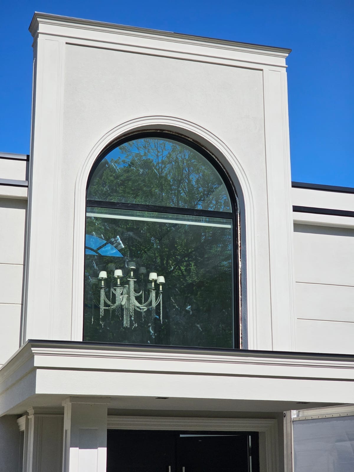 Detail of the arched window with chandelier visible through the glass